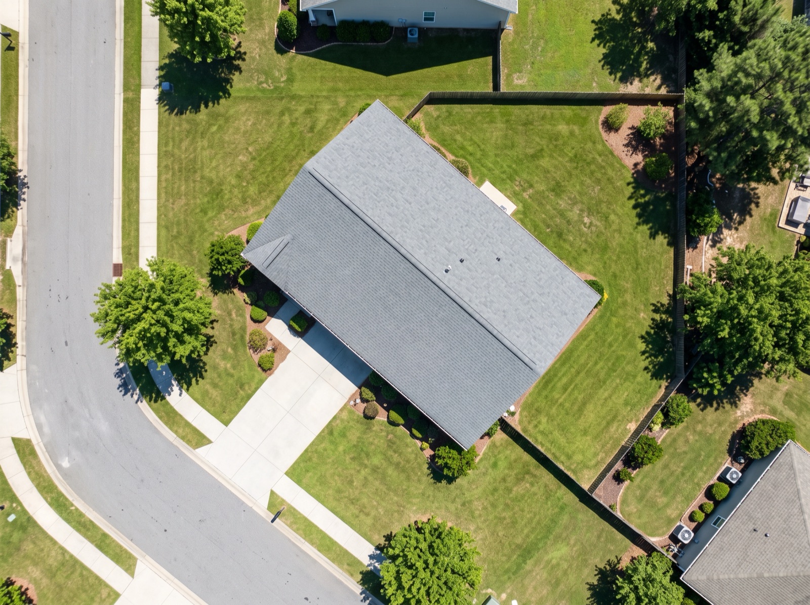 Straight-down satellite view of a single detached suburban house on its lot, with driveway, lawn, garden and street